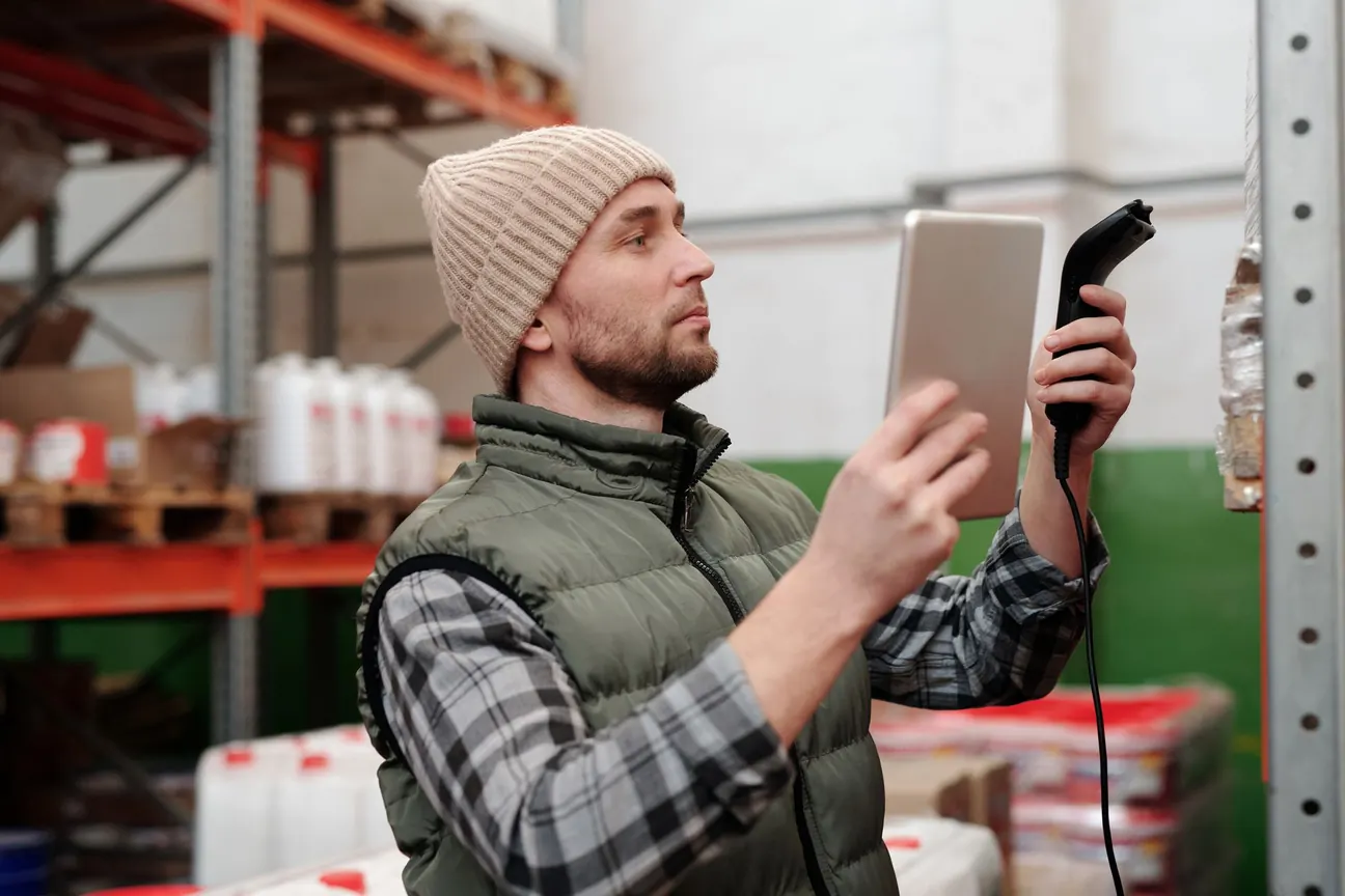 Mitarbeiter im Lager prüft Ware mit Tablet und Handscanner